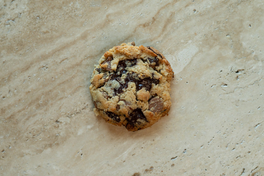 Chocolate chip cookie on a beige stone surface