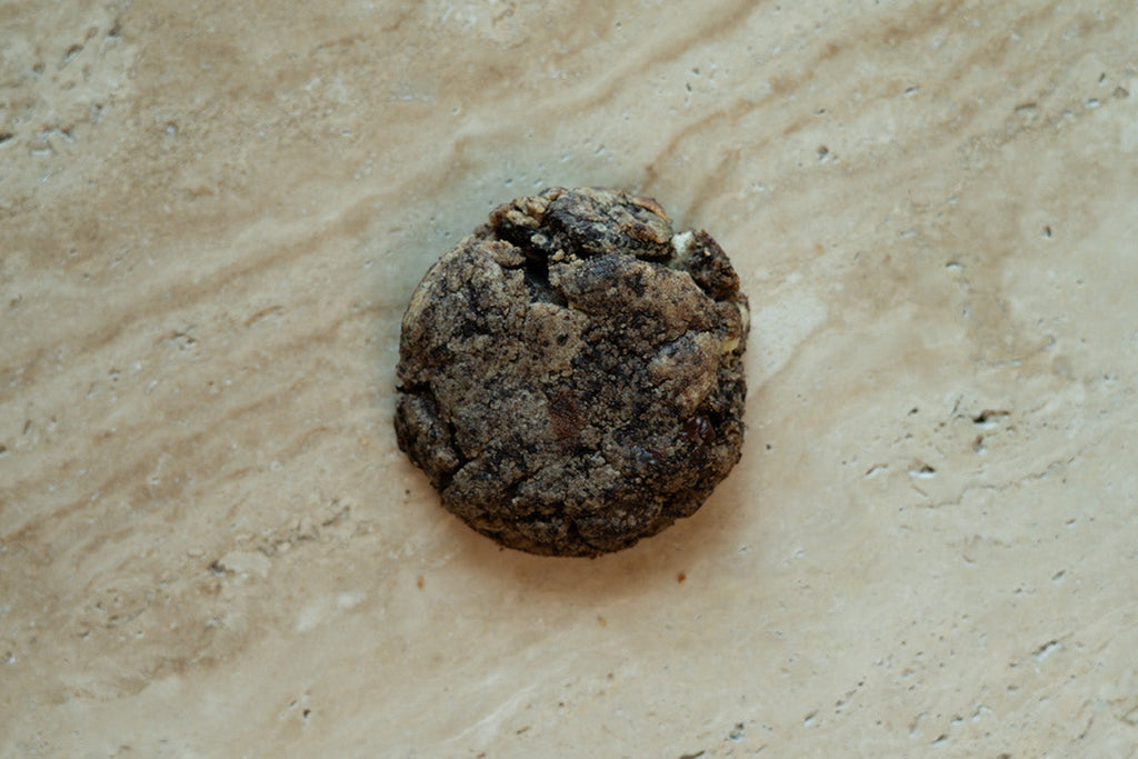 Small dark brown rock on a beige stone surface