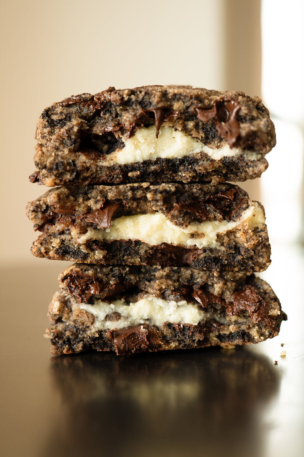 Stack of chocolate cookies with cream filling on a reflective surface