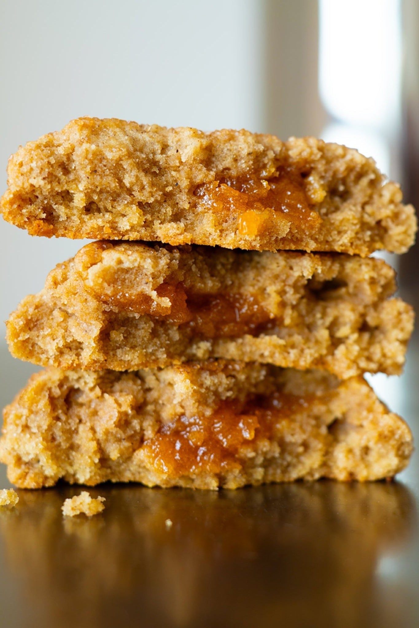 Stack of three cookies with a visible filling on a reflective surface.